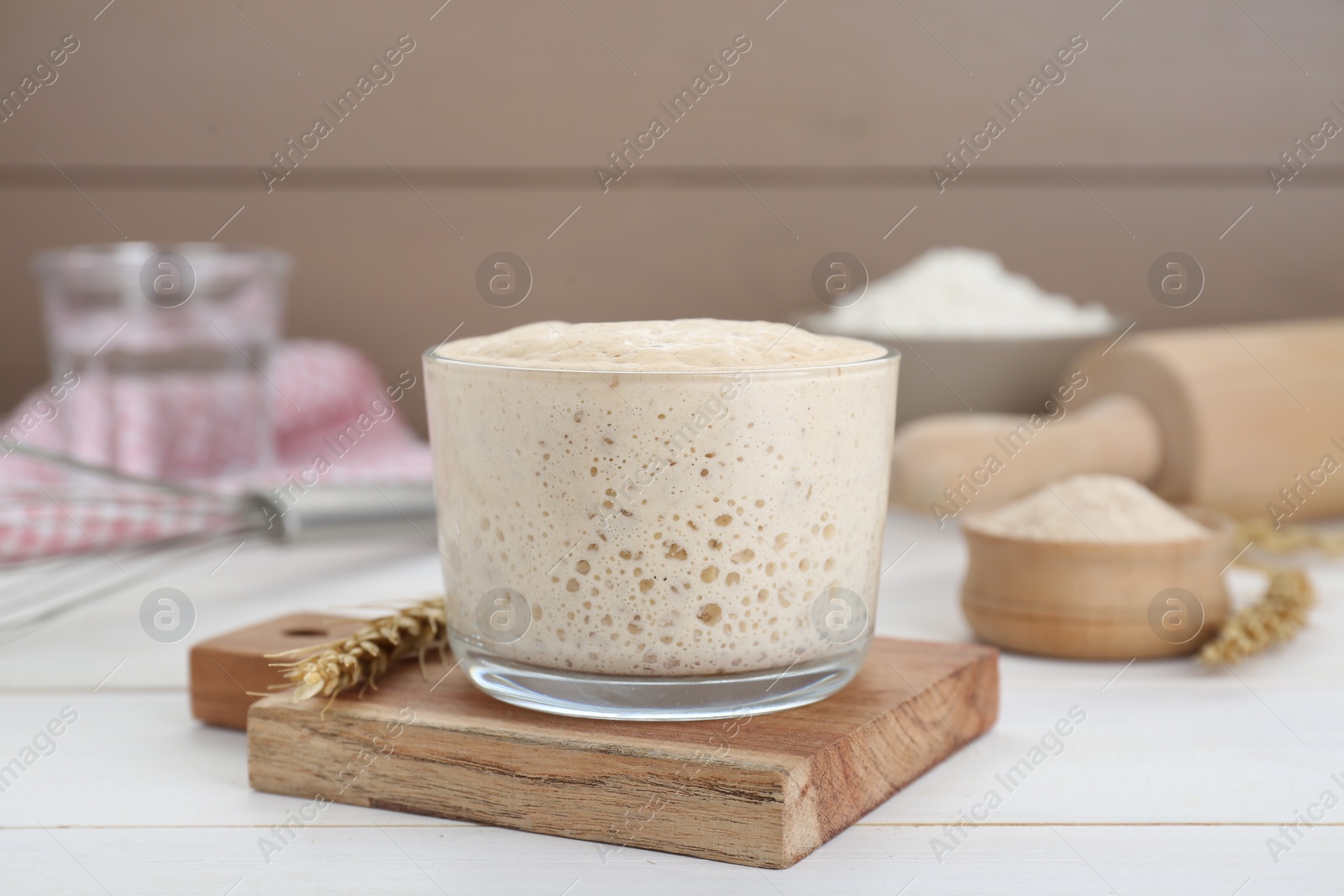 Photo of Leaven and ear of wheat on white wooden table