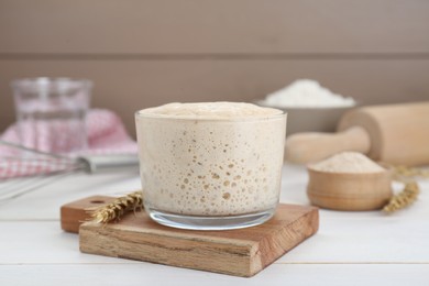 Photo of Leaven and ear of wheat on white wooden table