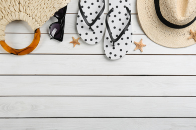 Flat lay composition with flip flops on white wooden background. Space for text