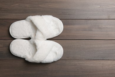Photo of Pair of soft slippers on wooden floor, top view. Space for text