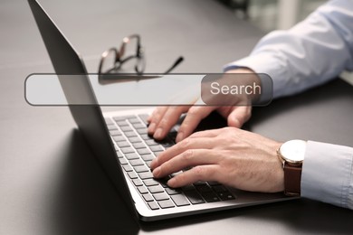 Image of Search bar of website over laptop. Man using computer at grey table, closeup