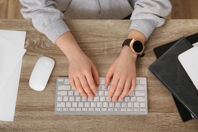 Photo of Young woman with smart watch working at table in office, top view