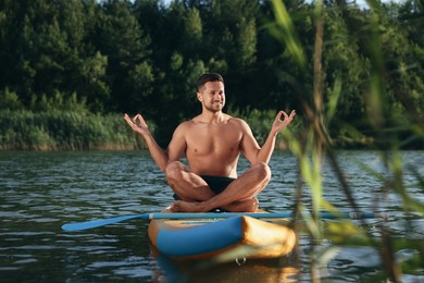 Photo of Man meditating on color SUP board on river