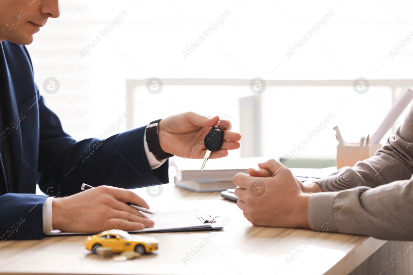 Photo of Salesman giving key to customer in office, closeup. Buying new car