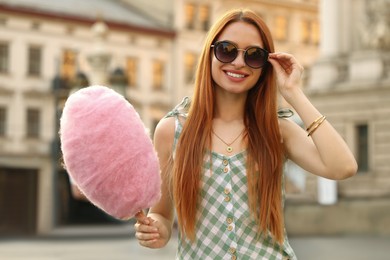 Photo of Smiling woman with cotton candy on city street