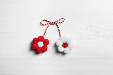 Traditional martisor with flowers on white wooden background, top view. Beginning of spring celebration