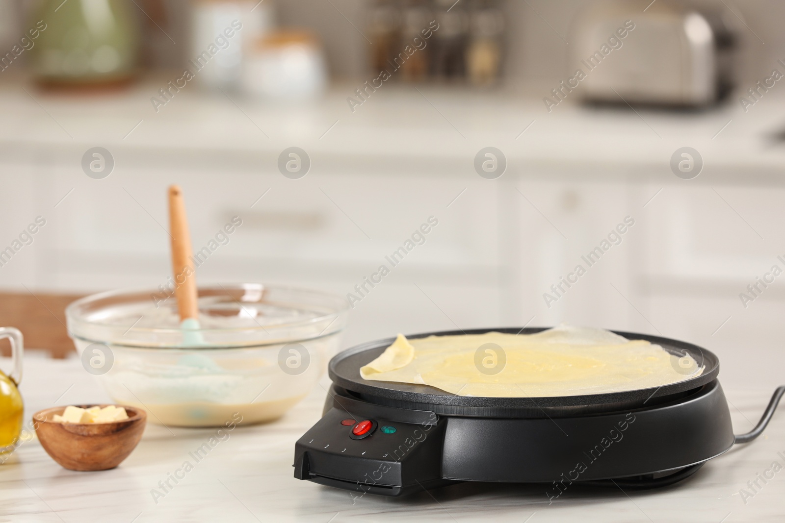 Photo of Cooking delicious crepe on electric pancake maker in kitchen. Space for text