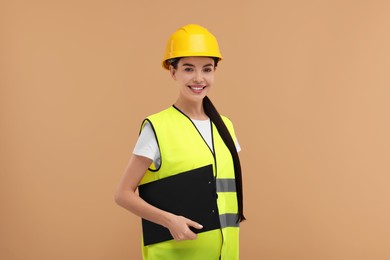 Engineer in hard hat holding clipboard on beige background