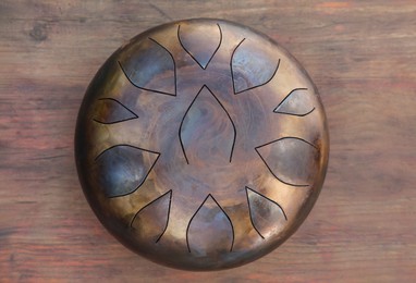 Photo of Steel tongue drum on wooden table, top view. Percussion musical instrument