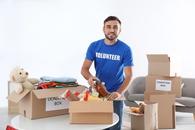 Photo of Male volunteer collecting donations at table indoors