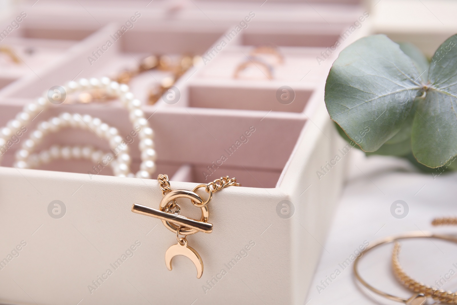 Photo of Jewelry box with stylish golden bijouterie on white table, closeup