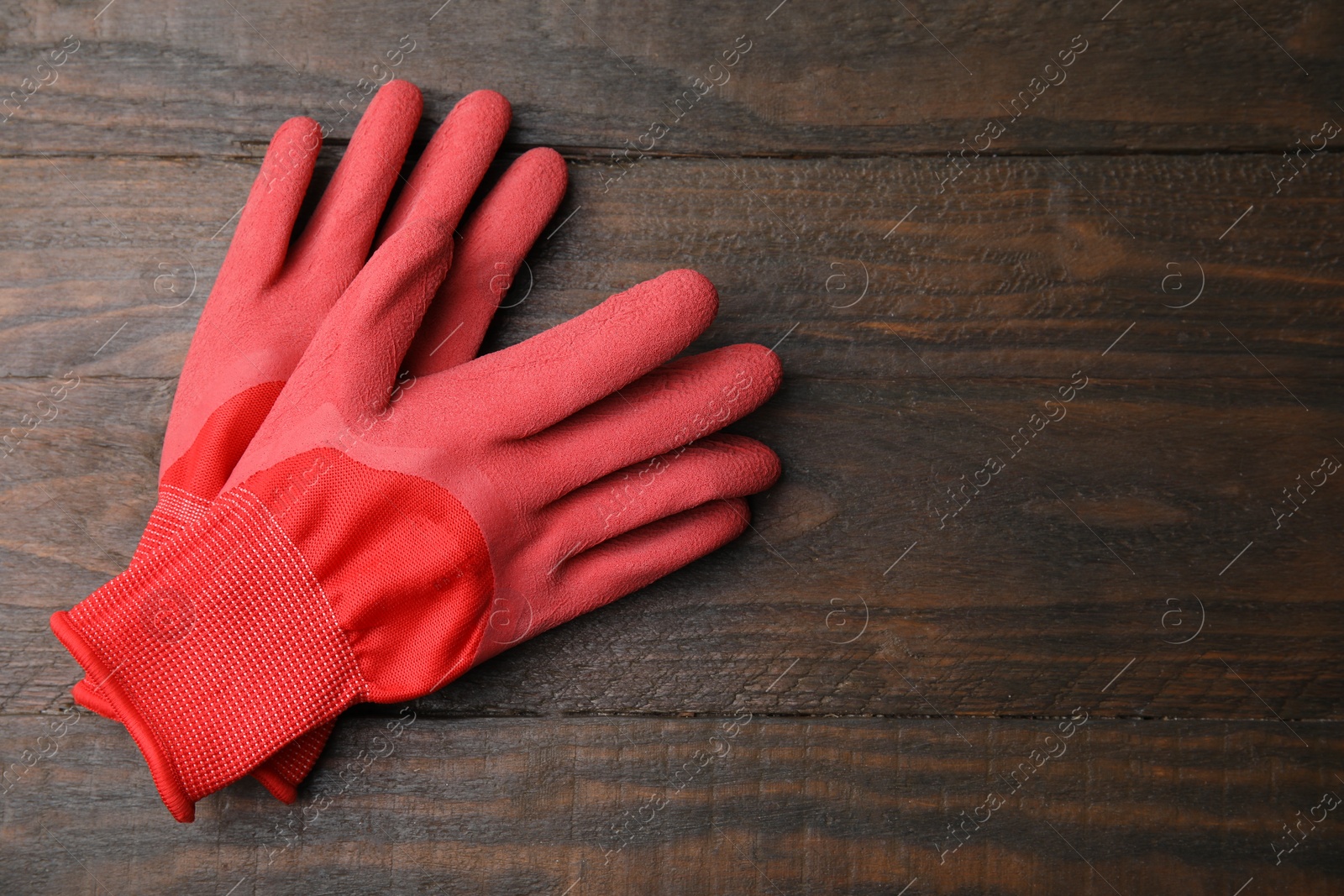 Photo of Pair of red gardening gloves on wooden table, top view. Space for text