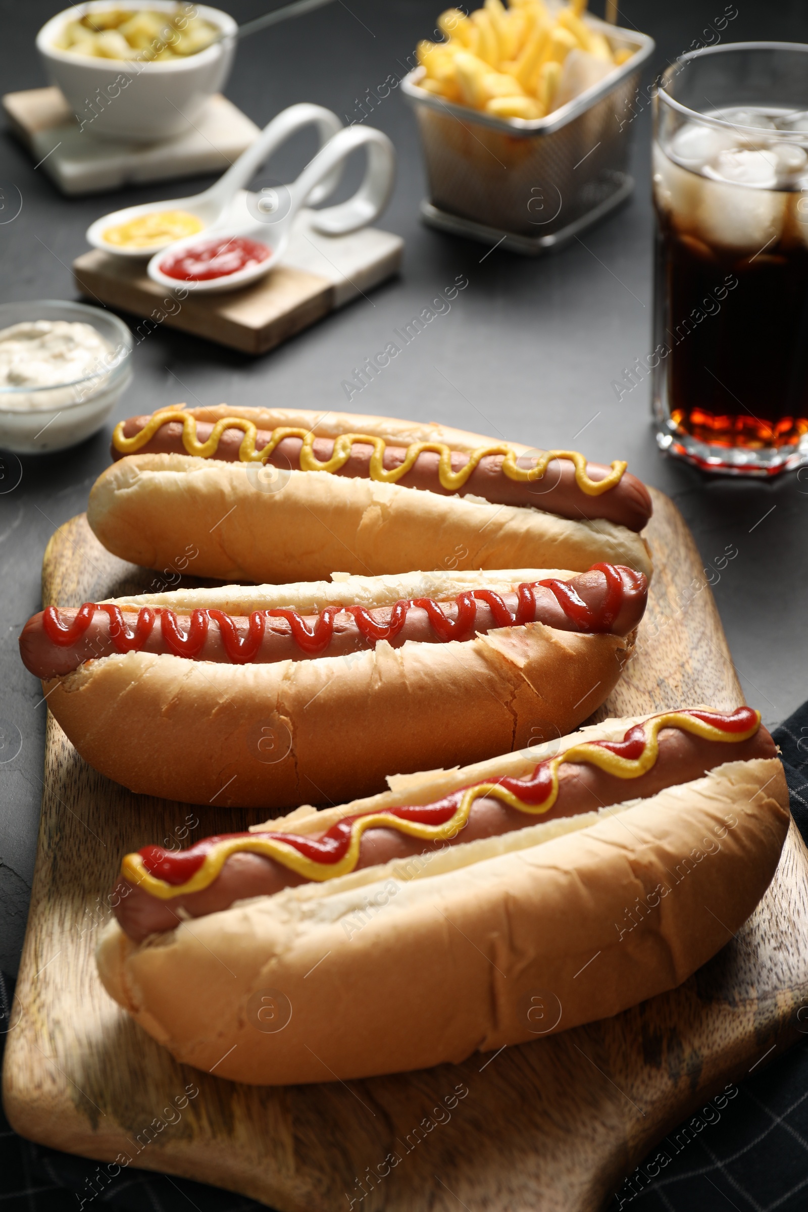 Photo of Fresh delicious hot dogs with sauces served on black table