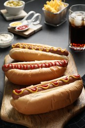 Photo of Fresh delicious hot dogs with sauces served on black table