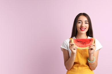 Beautiful young woman posing with watermelon on color background