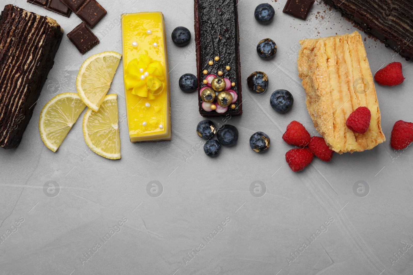 Photo of Flat lay composition with different tasty cakes on light grey table. Space for text