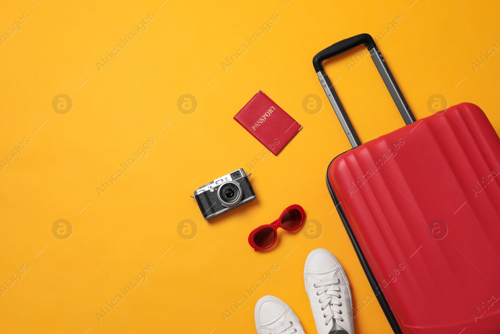 Photo of Flat lay composition with suitcase and travel accessories on yellow background, space for text. Summer vacation