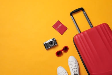 Photo of Flat lay composition with suitcase and travel accessories on yellow background, space for text. Summer vacation