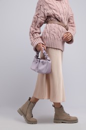 Fashionable woman with stylish bag on light background, closeup