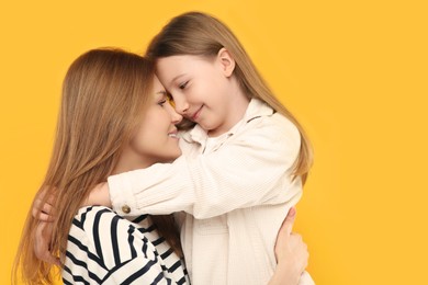 Photo of Portrait of happy mother and her cute daughter on orange background