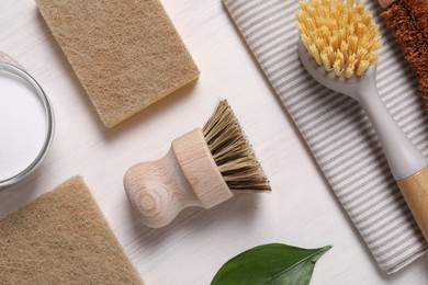 Photo of Cleaning brushes, sponges, towel, baking soda and leaves on light wooden table, flat lay