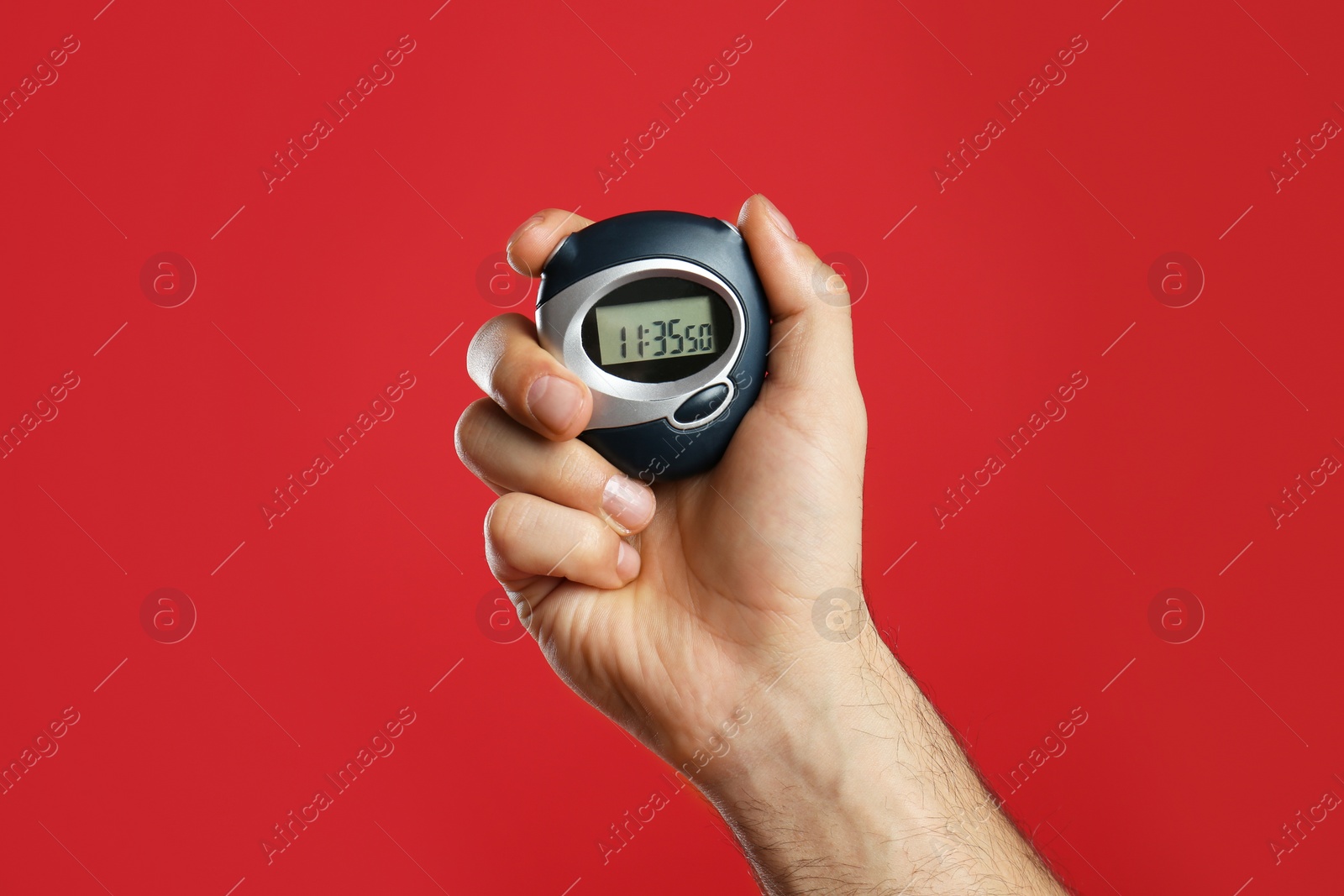 Photo of Man holding digital timer on red background, closeup