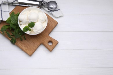 Photo of Delicious vanilla ice cream, mint and scoop on white wooden table, flat lay. Space for text