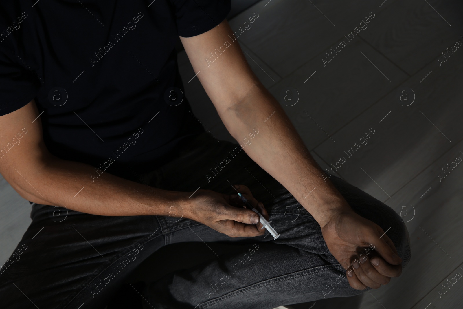 Photo of Male drug addict with syringe sitting on floor, closeup