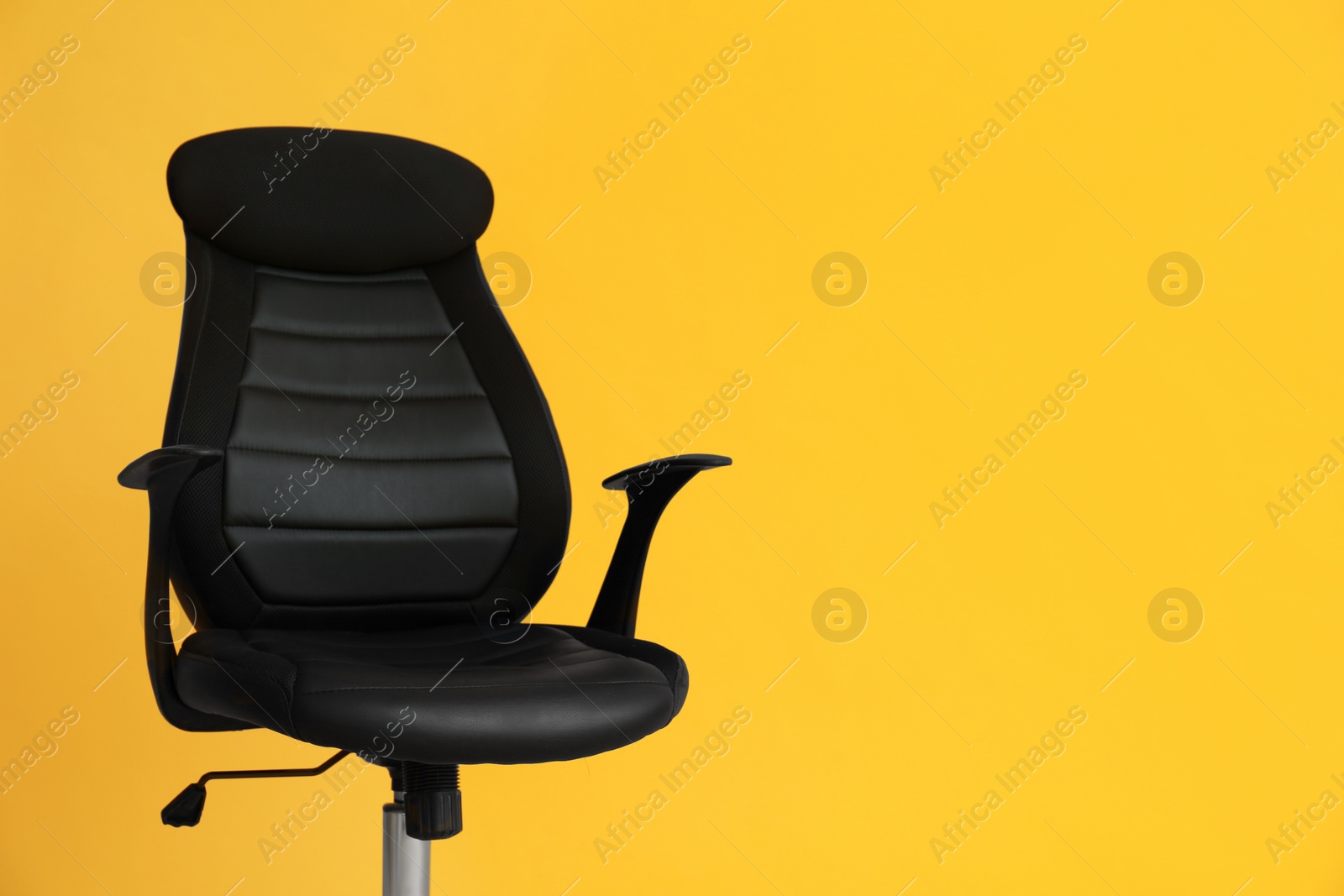 Photo of Modern office chair on yellow background. Space for text