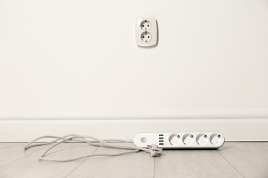 Photo of Extension cord near wall indoors, space for text. Electrician's professional equipment