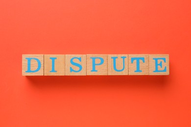 Photo of Word Dispute made with wooden cubes on red background, top view