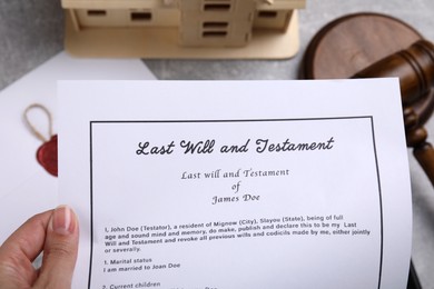 Photo of Woman holding last will and testament over table, top view