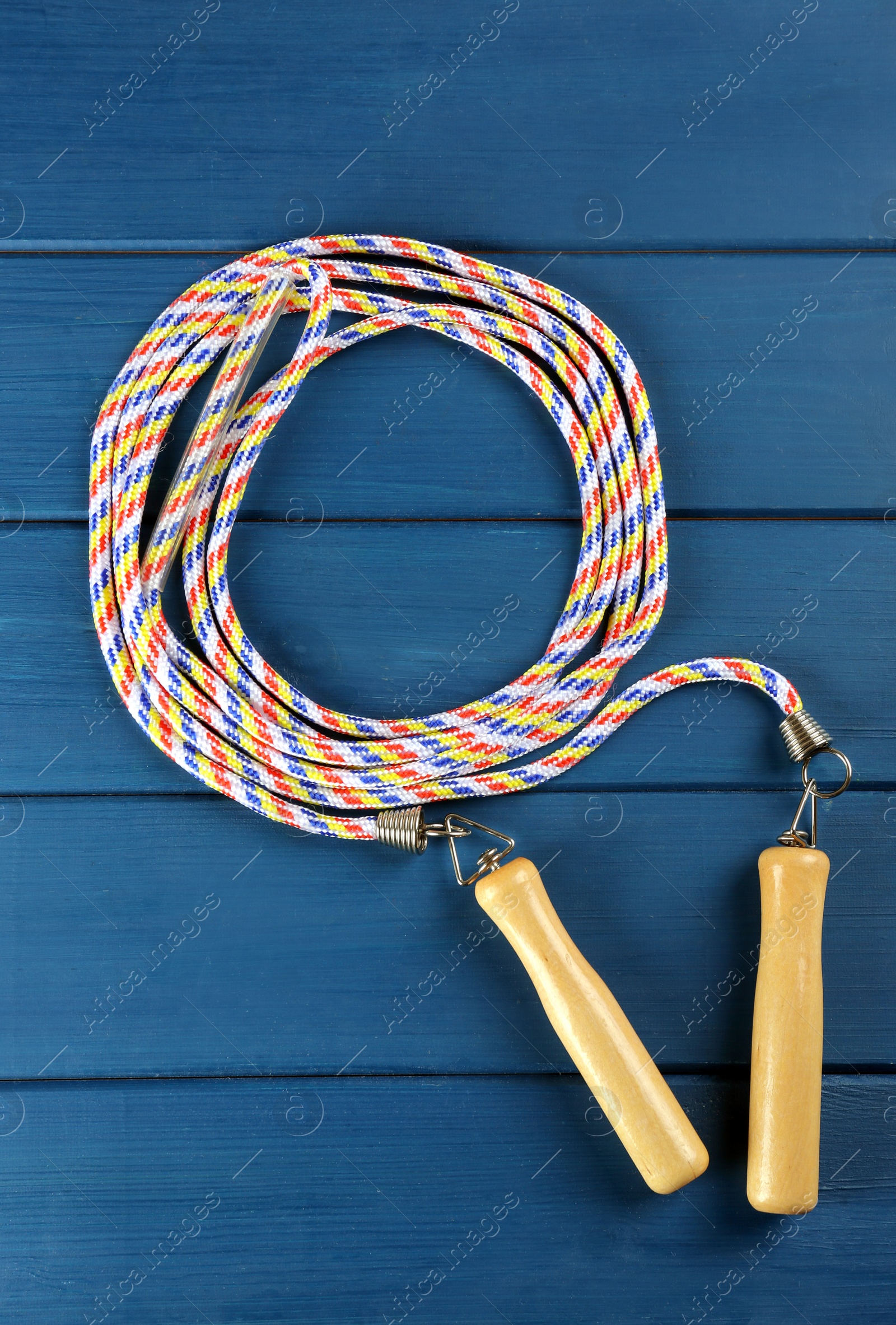 Photo of Skipping rope on blue wooden table, top view. Sports equipment