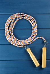 Skipping rope on blue wooden table, top view. Sports equipment