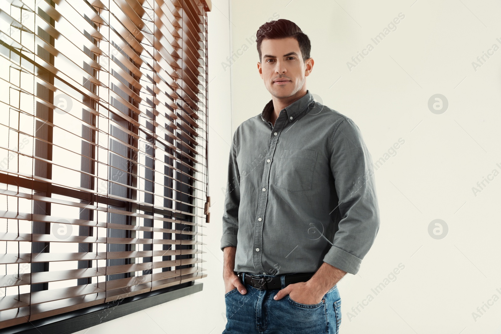 Photo of Portrait of handsome man at window indoors. Space for text