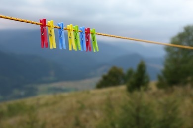 Photo of Colorful clothespins hanging on washing line in mountains