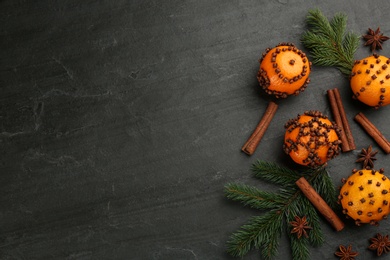 Photo of Flat lay composition with pomander balls made of fresh tangerines on dark table. Space for text