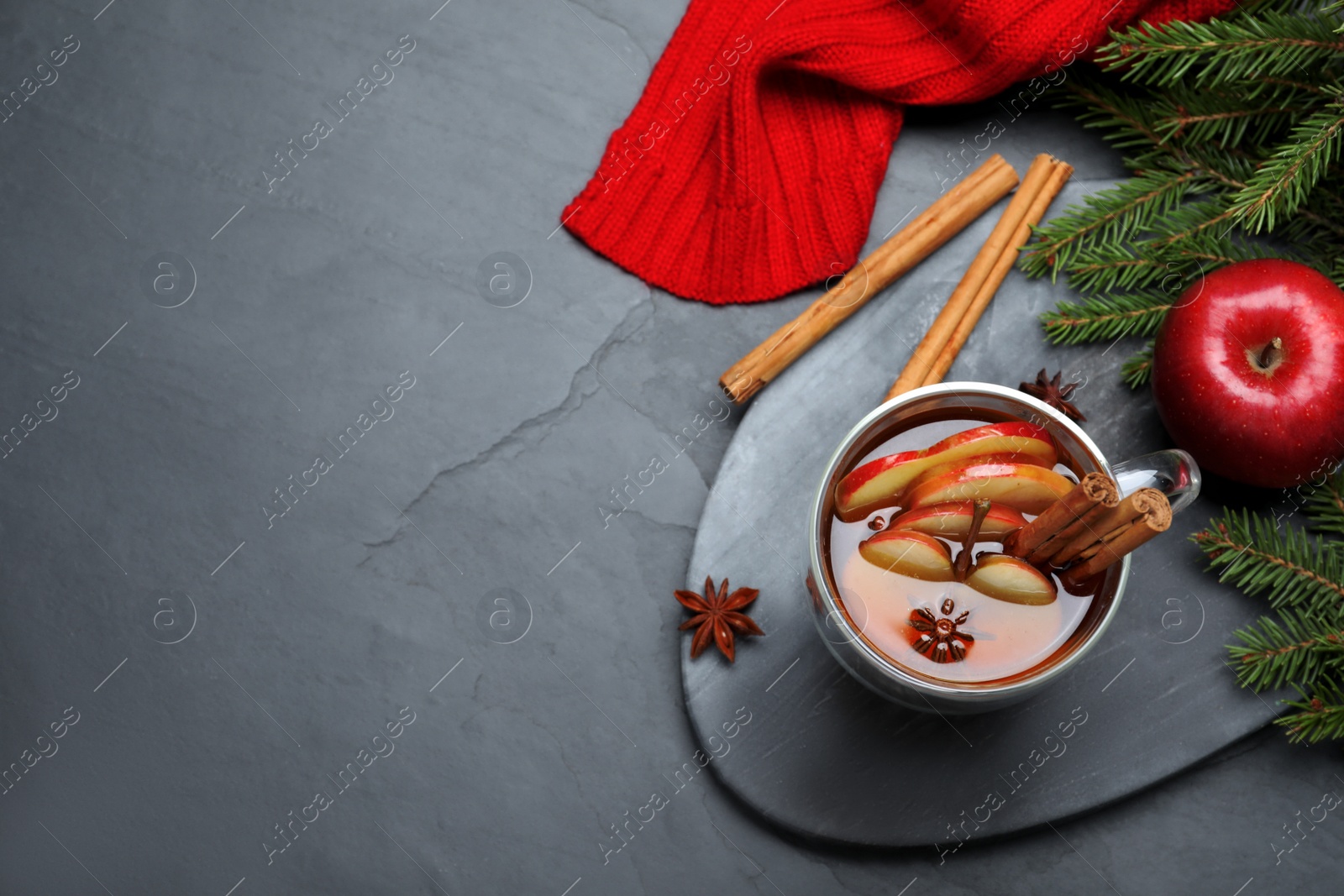 Photo of Aromatic hot mulled cider on black table, flat lay. Space for text