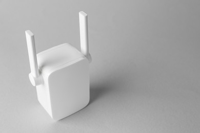 Photo of New modern Wi-Fi repeater on light gray background, space for text