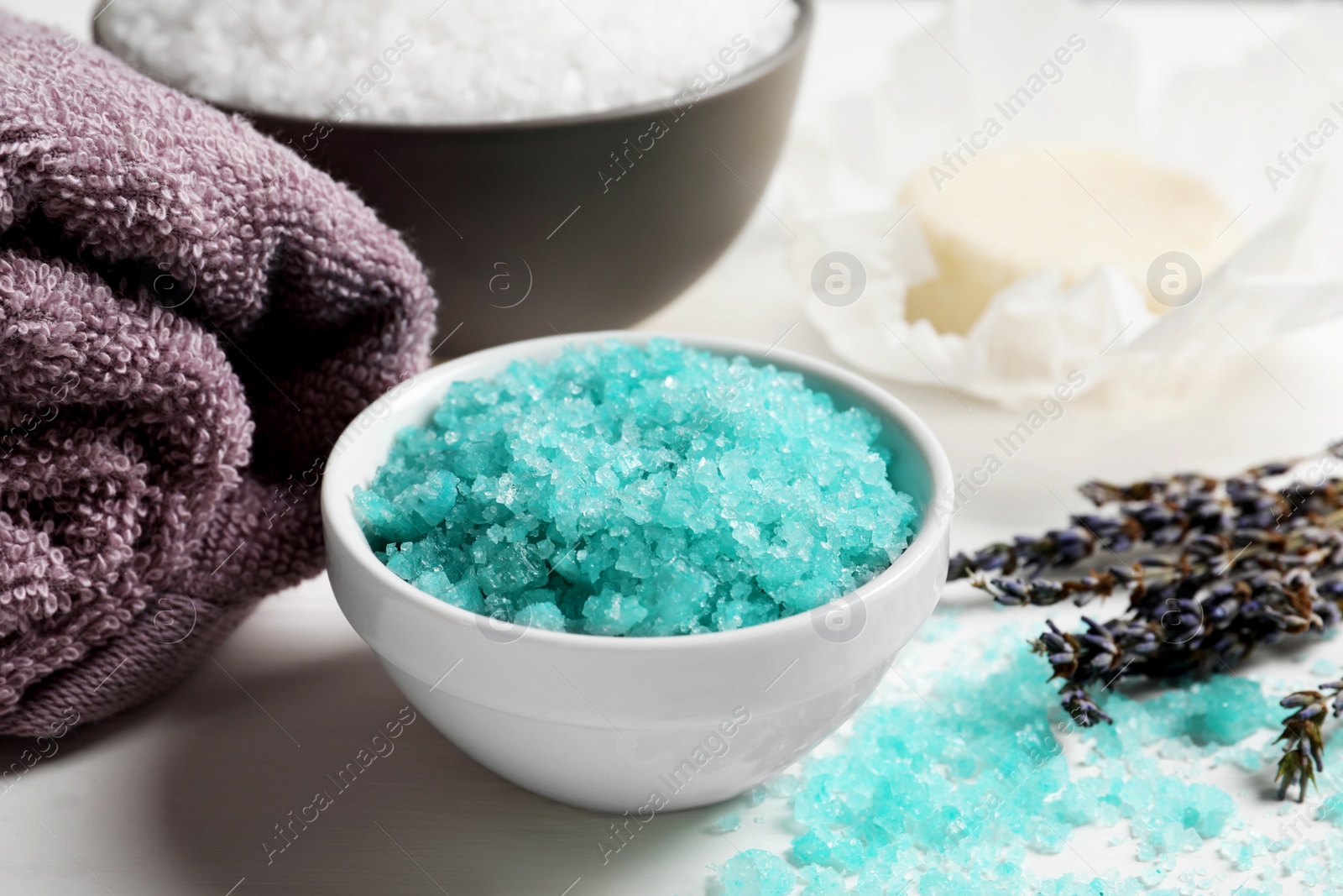 Photo of Beautiful turquoise sea salt, towel and dry flowers on white table