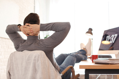 Young man relaxing at table in office during break