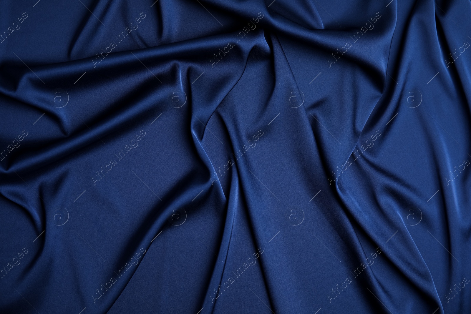 Photo of Crumpled dark blue silk fabric as background, top view