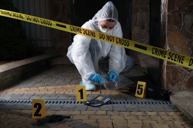 Photo of Criminologist working with evidences at crime scene outdoors