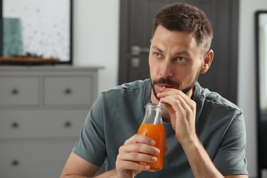 Photo of Man drinking delicious juice at home, space for text