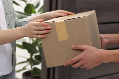 Photo of Courier giving parcel to receiver indoors, closeup