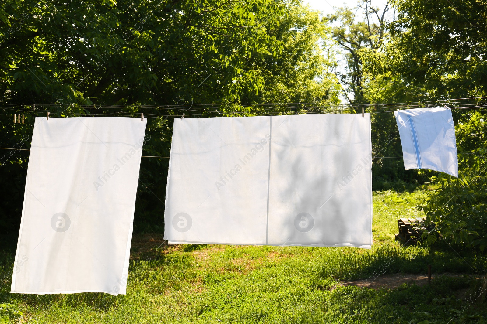 Photo of Washing line with clean laundry and clothespins outdoors