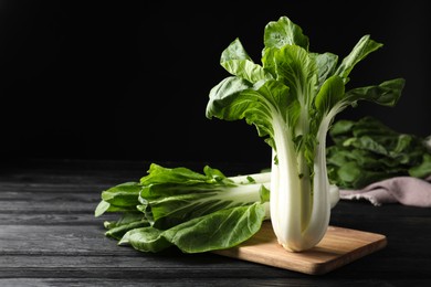 Photo of Fresh green bok choy cabbages on black wooden table. Space for text