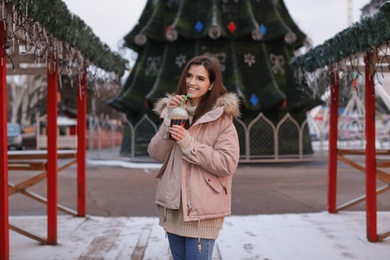 Photo of Woman with cup of mulled wine at winter fair