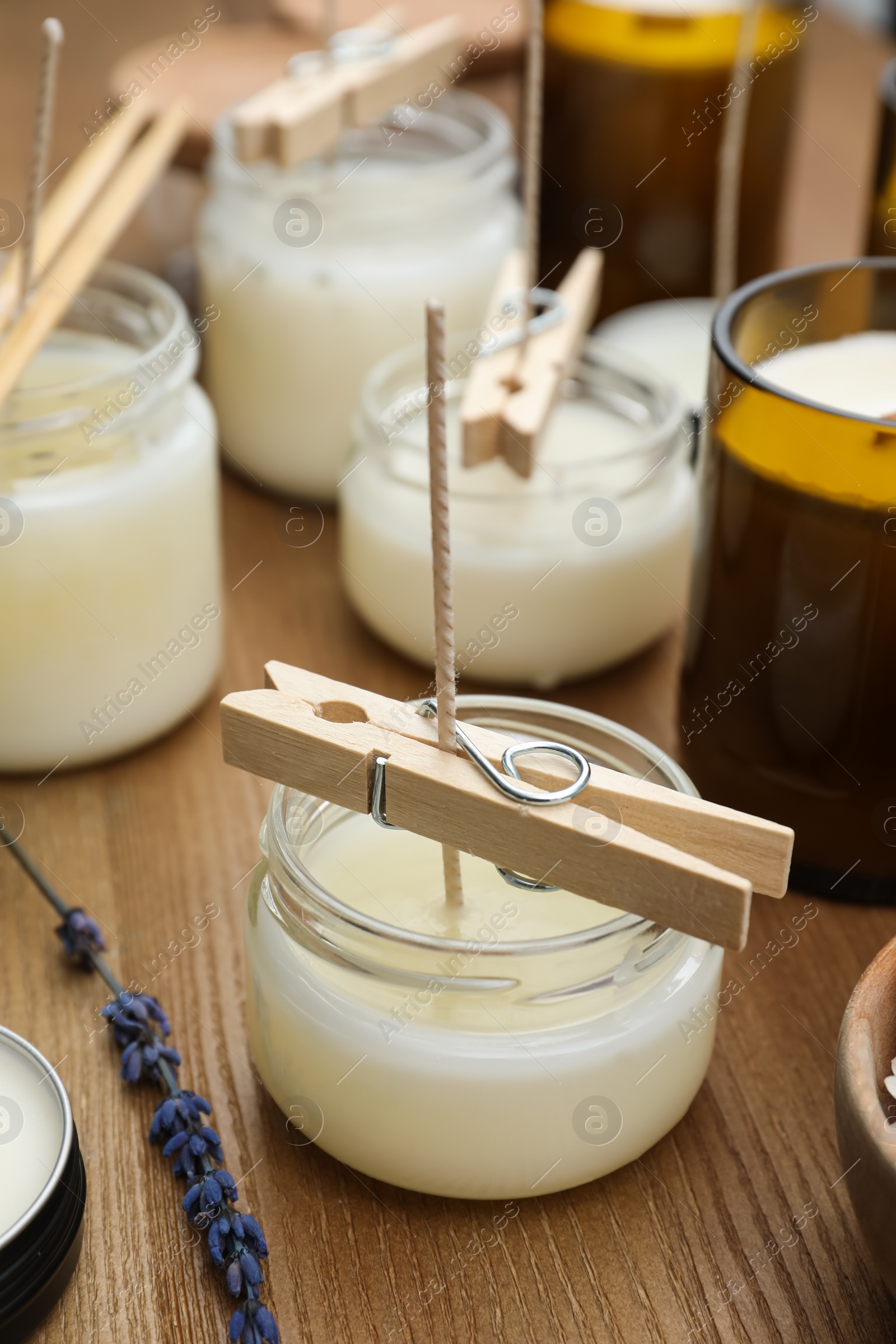 Photo of Glass jars with wax on wooden table. Handmade candles