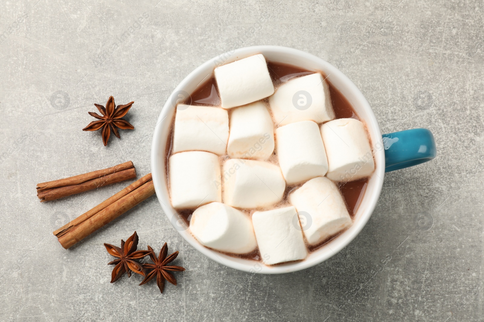 Photo of Tasty hot chocolate with marshmallows and spices on light grey table, flat lay